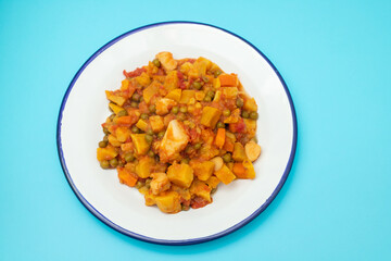 squid stew with vegetables in white dish on blue