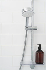 Shower rack with hanging shower head and shelf with bottle of gel.