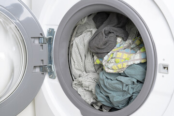 Washed cotton bed linen and towels in washing machine drum, close up.