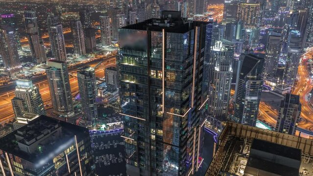 Dubai Marina and JLT district with traffic on highway between skyscrapers aerial night timelapse.
