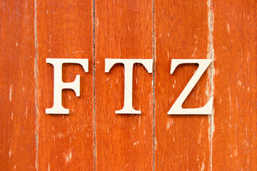 Alphabet letter in word FTZ (Abbreviation of Free trade zone) on old red color wood plate background