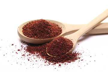 Ground sumac spice, pile in wooden spoon isolated on white 