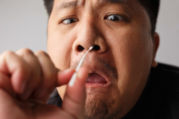 Asian men try to using Rapid Antigen Test Kit (ATK) by himself and painful emotion on his face