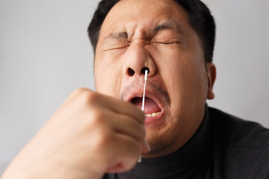 Asian men try to using Rapid Antigen Test Kit (ATK) by himself and painful emotion on his face