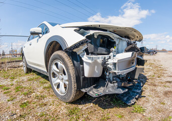 Artistic view of the car crash. Wide angle lens close up of the vehicle front after accident. Front of white car damaged, smashed by road accident. Wreck of the automobile destroyed front frame.