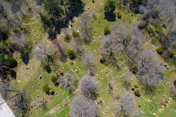 Aerial top very high view of modern cemetery at the city. Small headstones and crosses at graveyard with gravestones.