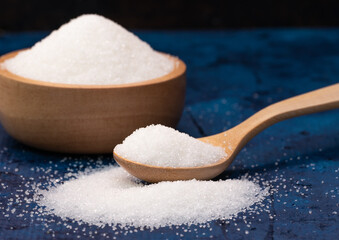 close up white sugar in wooden spoon.