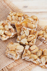 Peanut brittle, an old school sweet favorite, cut into small bars on rustic type surface with copy space