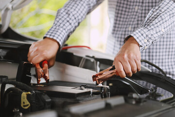 A mechanic  is charging car battery pot