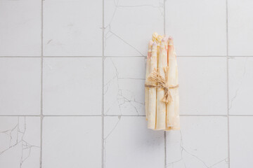 Organic white asparagus on a white tiles  background. Healthy food.