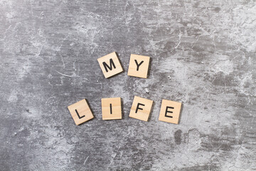 My Life texto escrito en cubos de madera sobre un fondo gris rústico. Vista superior y de cerca....
