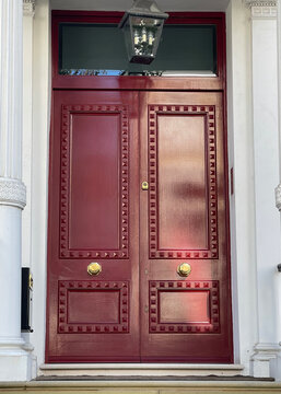 A Grand Red Double Door With White Trim.