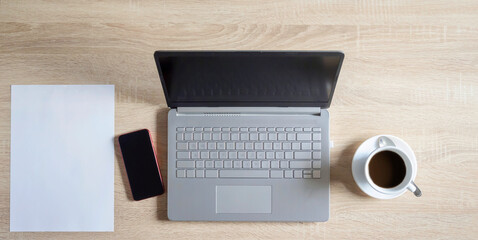 Table with laptop, mobile phone and a coffee.