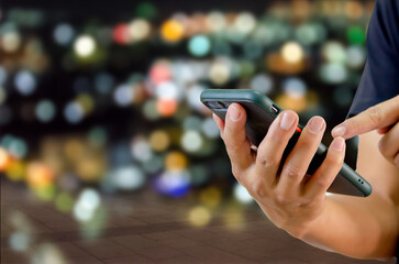 man using mobile phone in the street in the background night light.