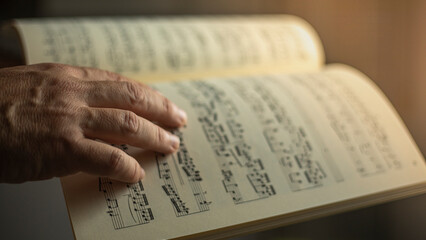 Photograph showing close-up of an older man's hand caressing a classical music sheet with musical...