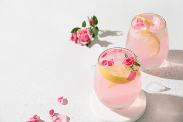 Pink rose cocktails, drinks or lemonade with rose flowers on white sunny background. Close up. Copy space.