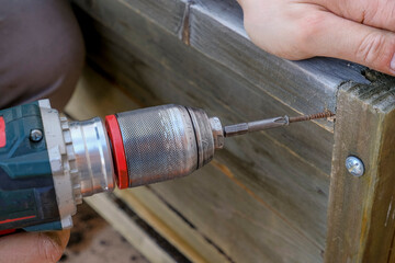 drilling tool in man's hands working close-up. Drilling hole in wooden plank. Construction and building equipment and work