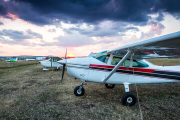 Fototapeta na wymiar Small private airplanes parked at the airfield at scenic sunset
