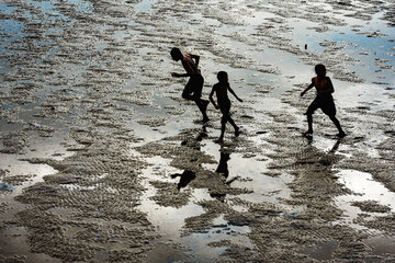 Fototapeta na wymiar Silhouettes of children running on Pattaya beach during low tide in Thailand.
