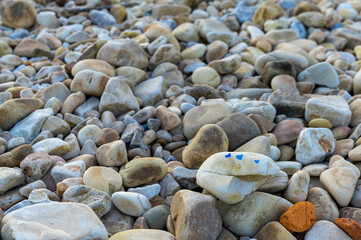 close-up view of a field of rocks and pebbles with colorful hearts painted on one rock