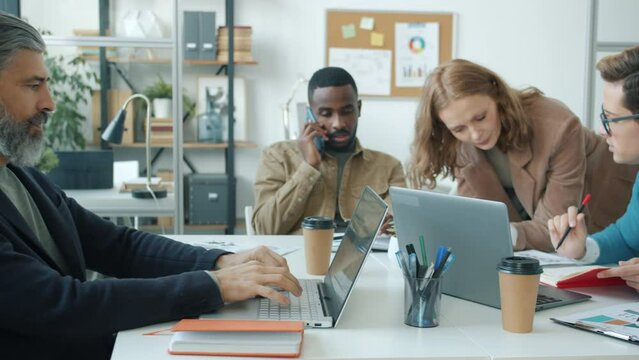 Group of office workers busy with routine activities using laptops talking on mobile phones and discussing work in modern room. People and job concept. - Powered by Adobe
