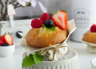 Muffin with fresh berries on the table with strawberries, blueberries, raspberries and mint close up