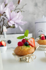 Muffin with fresh berries on the table with strawberries, blueberries, raspberries and mint close up