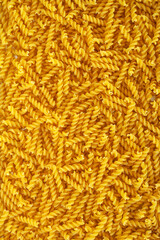 Uncooked fusilli spiral pasta noodles background
