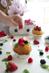 Muffin with fresh berries and a female hand takes a berry close up