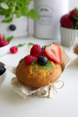Muffin with fresh berries on the table with strawberries, blueberries, raspberries and mint close up