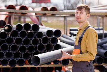 man builder contractor is choosing a sewage pipe from pipes store and preparing for sewer...