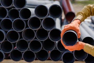 plumber hands choosing a pipe for sewage on construction site.