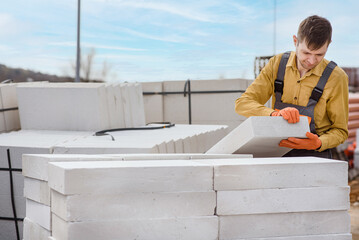  man contractor builder is holding an autoclaved aerated concrete block aac on a construction site.