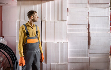 man builder is holding a styrofoam insulation sheet and prepare for building isolation for energy...