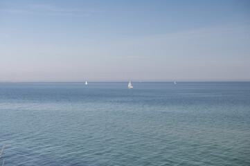 Fototapeta na wymiar Blue sky without clouds with clear water and sailboards away from the coast in north Germany