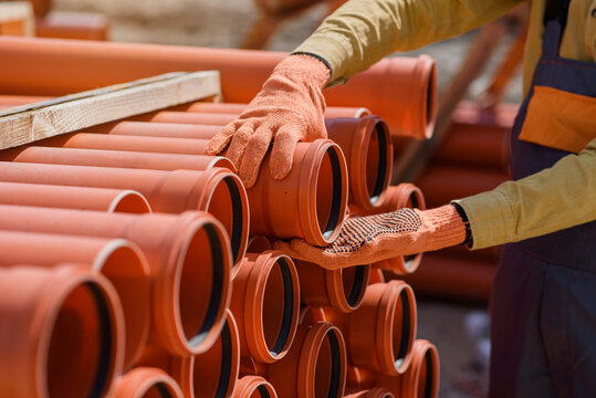 plumber hands choosing a pipe for sewage on construction site.