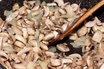 Sliced mushrooms champignons with onions are fried in a pan. Cooking food