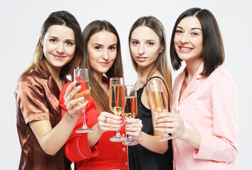 four beautiful young women dressed in pajamas drink champagne and have fun