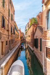 Fototapeta na wymiar Quiet street and narrow canal with boats along brink. The residential area of Venice, Italy.