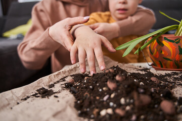 Boy stretching hands and looking with interest how his mother replacing flowers