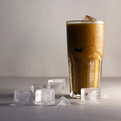 Tasty iced coffee with milk, cold drink in a glass with ice on a grey background