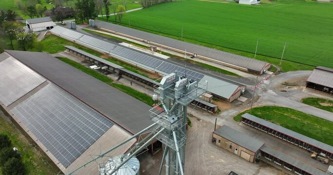 Grain elevator feed mixing mill at large rural farm operation for dairy hogs poultry in USA. Rooftop solar arrays. Agriculture theme in America. Aerial drone pullback reveal ag industry.