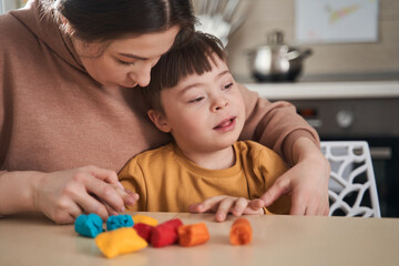 Concentrated caucasian woman playing with her son at the kitche