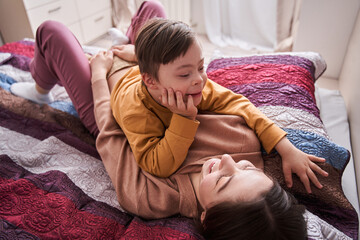 Mom enjoying time with her son, while laying at the bed and looking at him