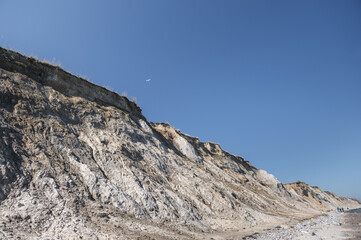 Beauty of big precipice at blu clear sea with stones beach