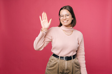 Smiling short haired girl wearing glasses is waving nicely to the camera. © Vulp