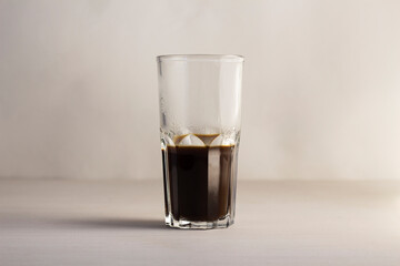 Transparent glass cup with black coffee. Dark liquid in a glass
