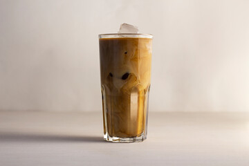 Cream is mixed with coffee in a glass. Ice coffee. Delicious refreshing drink