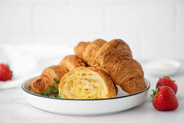 croissants with fresh strawberries and jam on a wooden board