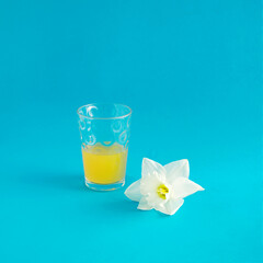 glass of lemonade with white flower on blue background 